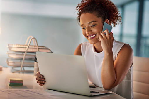 Woman smiling at laptop while on the phone