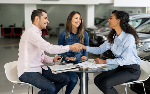 Young couple closing deal with a car saleswoman.