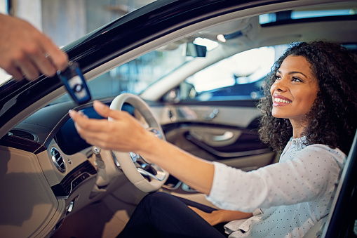 Car dealer is giving key for a new car to a businesswoman
