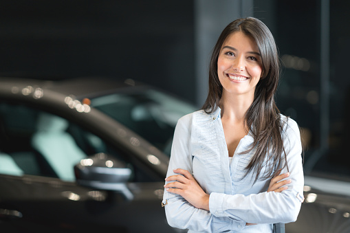Portrait of a happy Latin American woman buying a car at the dealership